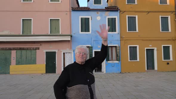 Happy Italian senior woman waving to the camera alt