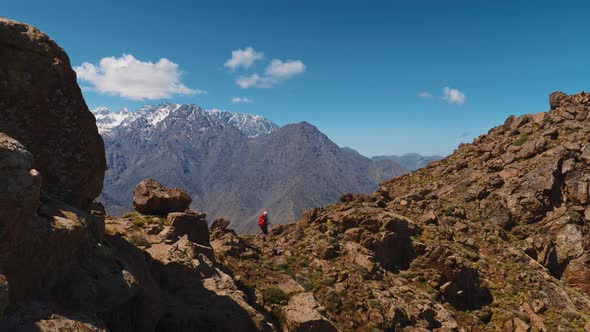 Tourist backpacker hiking in High Atlas with Toubkal massif in the distance alt