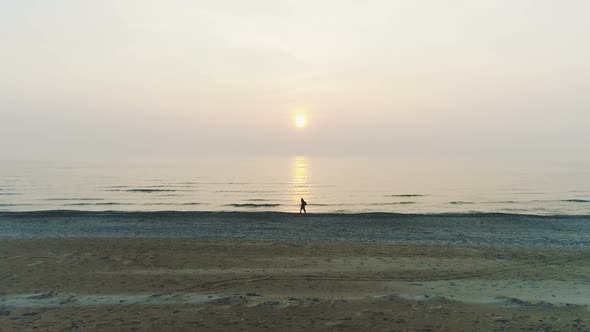 People Walking Along Seaside During Sunset