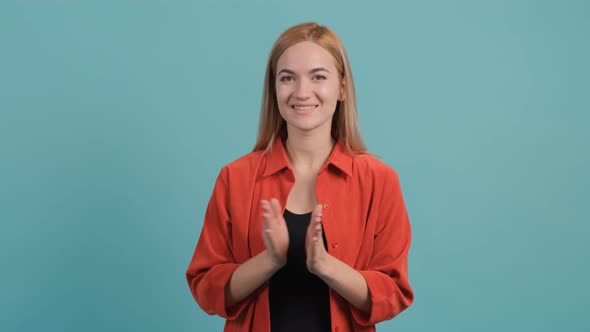 Pretty Girl with Blond Hair Applauds While Sitting on the Turquoise Background alt