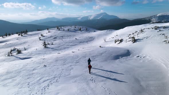 Drone Following Couple of Hikers, Walking on Mountain Plateau in Winter