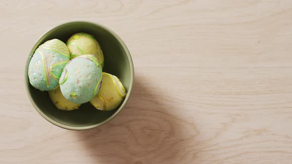 Video of decorated colorful easter eggs in bowl on a wooden surface alt