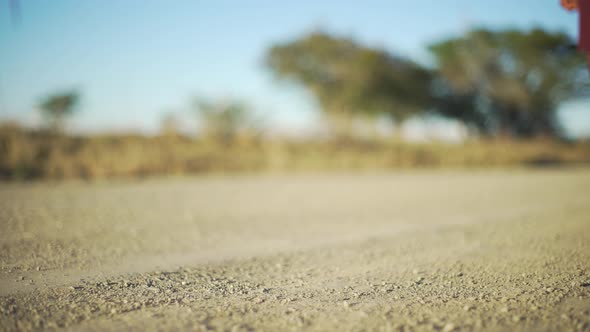 Feet of school girl walking on a gravel road. alt