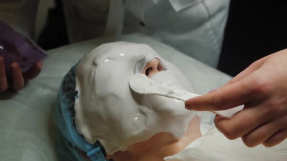 Doctor Beautician Applies a Cream Mask on the Patient's Face