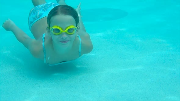 The Little Girl in the Swimming Pool Underwater and Smiling alt