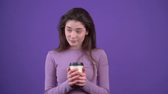 The Beautiful Young Woman Holds the Coffee Cup Tightly Looks Down Then Thinks to One Side Drinks alt