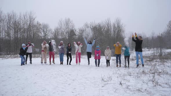 Group people jumping up throwing snow with their hands in snowy forest in winter