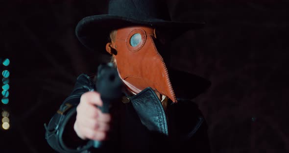 Person in a Hat Leather Coat and a Plague Doctor Mask Aims a Gun at a Victim or Enemy and Then