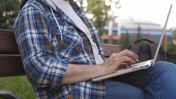 A Male Freelance Programmer Works on a Laptop in a Park