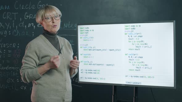 Portrait of Mature Woman Teaching Online Class Explaining Software Development Pointing at Digital alt