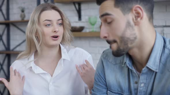 Serious Slim Beautiful Woman Talking with Blurred Man Gesturing and Pointing at Smartphone alt