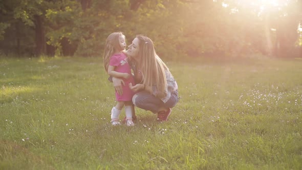 Little Kid with Long Hair Sitting on Front of Her Mother