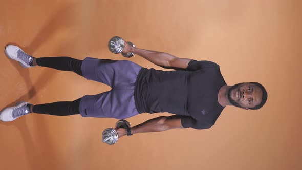 An AfricanAmerican Man Lifts Dumbbells on an Isolated Background