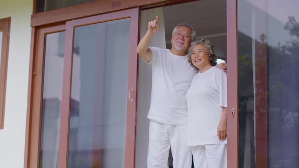 Happiness Two Asian couple elder with white hairs standing beside windows together and looking bird alt