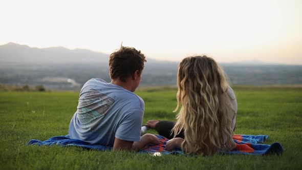 Shot of cute boyfriend and girlfriend laying on a blanket and having a picnic on the grass. alt