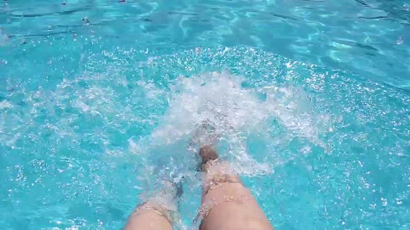 Women's Feet in the Pool Splashing and Creating a Lot of Splashes Slow Motion