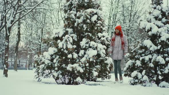 Slow Motion Beautiful Smiling Young Woman in Parka Knitted Red Beanie and Mittens Walks with Her alt