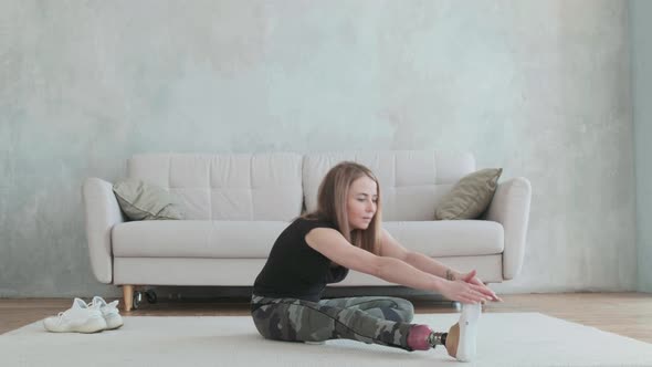 Young  woman with prosthetic leg does stretching back bending exercise