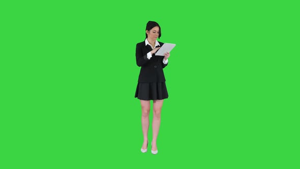 Cute Woman in Skirt Dancing and Using Digital Tablet on a Green Screen, Chroma Key. alt