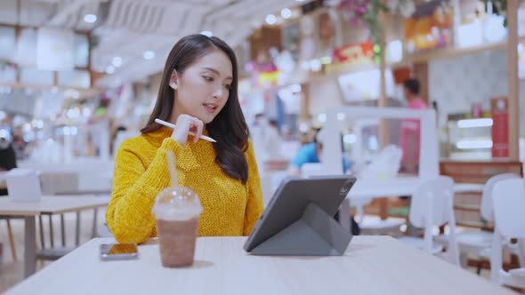 Business owner or freelance using a smartphone tablet working in food court public area