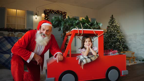 Jocund Santa Claus Showing Thumbs Up and Dreaming  Girl.