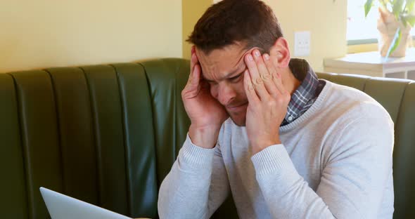 Depressed man using laptop alt