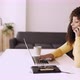 Young Woman Using Mobile Phone While Working on Laptop at Home Office - VideoHive Item for Sale