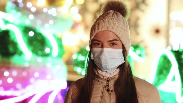 Close up Portrait of Caucasian Female in Medical Mask Standing in Decorated Xmas City alt