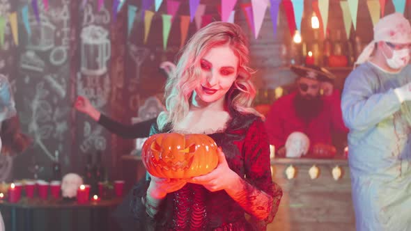 Sexy Vampiress with a Jack-o-lantern in Her Hands at a Halloween Party alt