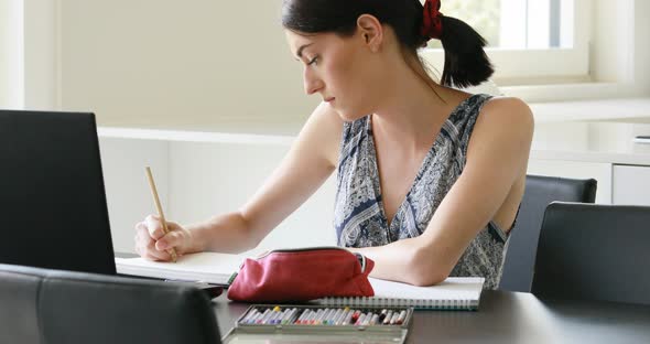 cute minute girl works or studies with computer and pencil