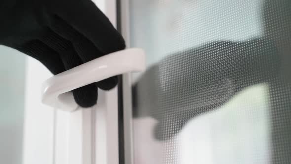 A Blackgloved Hand Opens a Blue Plastic Door alt