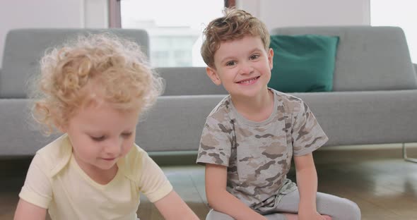 Close Up of a Little Boy and a Little Girl Who are Drawing on the Floor Girl is Looking at Her alt