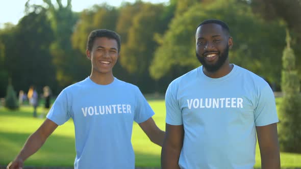 Young Male Volunteers Showing Arm Muscles, Strength Gesture, Teamwork Support alt