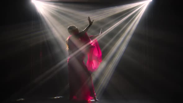 Silhouette a Young Girl Dancer in a Red Sari. Indian Folk Dance. Shot in a Dark Studio with Smoke alt