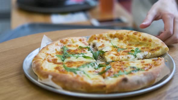 close-up female hand takes a piece of cheese pizza