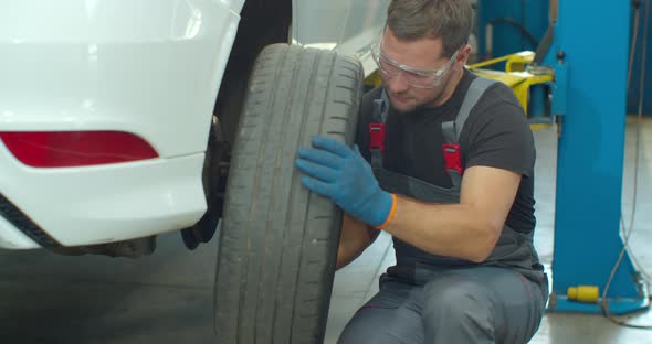 Mechanic Is Unscrewing Lug Nuts with a Pneumatic Impact Wrench. Specialists Removes the Wheel in alt