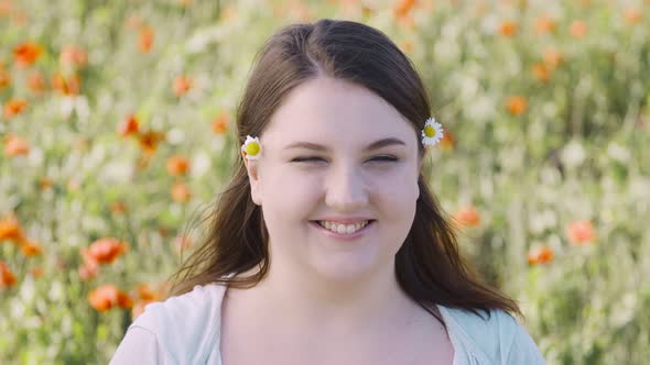 Portrait of a Young Pretty Fat Smiling Woman Against the Background of a Field of Wild Poppies with alt