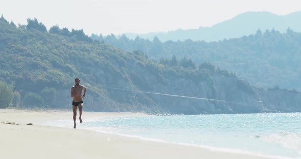 The Handsome Man with a Perfect Athletic Body in Swimming Trunks Having Fun on a Deserted Beach in alt