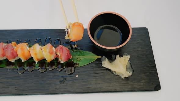 Chopsticks Dipping Sushi Roll Into Soy Sauce