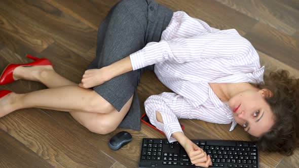 Tired Young Female Office Manager is Lying on the Floor with Keyboard Mouse and Smartphone Lay Flat alt
