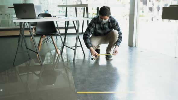 Male workers preparing masking tape to symbolize social distances.