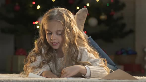 Little Girl Putting Letter to Santa Into Envelope, Faith in Christmas Miracle alt