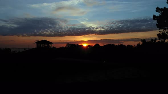 Rising aerial shot of cliffs and coast line at stunning golden sunset with epic cinematic style. alt