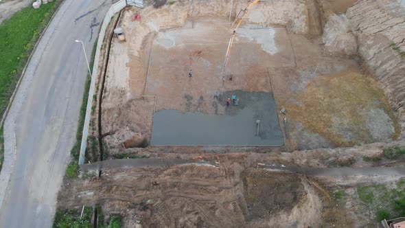 Aerial view construction workers pouring concrete at construction site basis. alt
