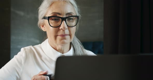 Elderly Woman with Laptop and Coffee