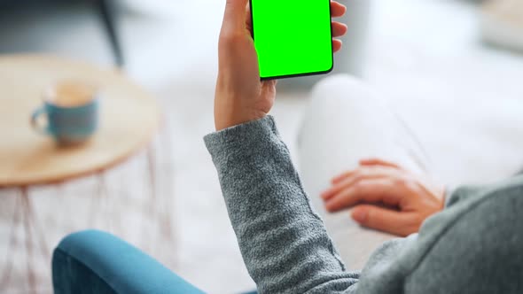 Woman at Home Using Smartphone with Green Mockup Screen in Vertical Mode alt
