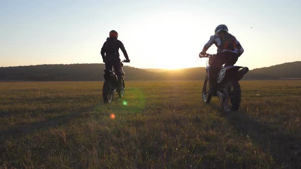 Two Motorcyclists Passing Through Large Field with Beautiful Landscape at Background. Bikers Rides alt