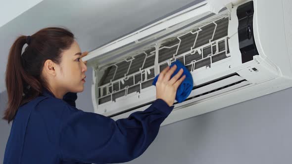 female technician service cleaning the air conditioner with cloth