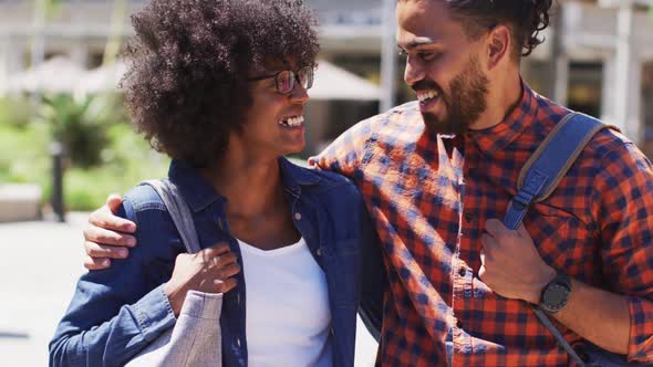 Diverse couple walking on the street holding hands smiling and talking alt
