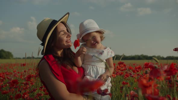 Happy Mother with Her Daughter in a Poppy Field